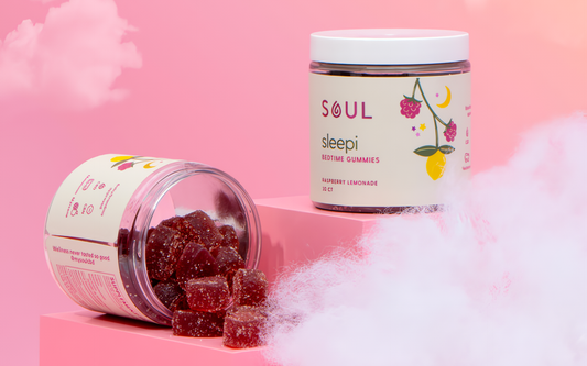 Front-right view of Soul Sleepi bedtime gummies jar showcasing an opened jar with raspberry lemonade gummies spilling onto a pink, cloud-like backdrop