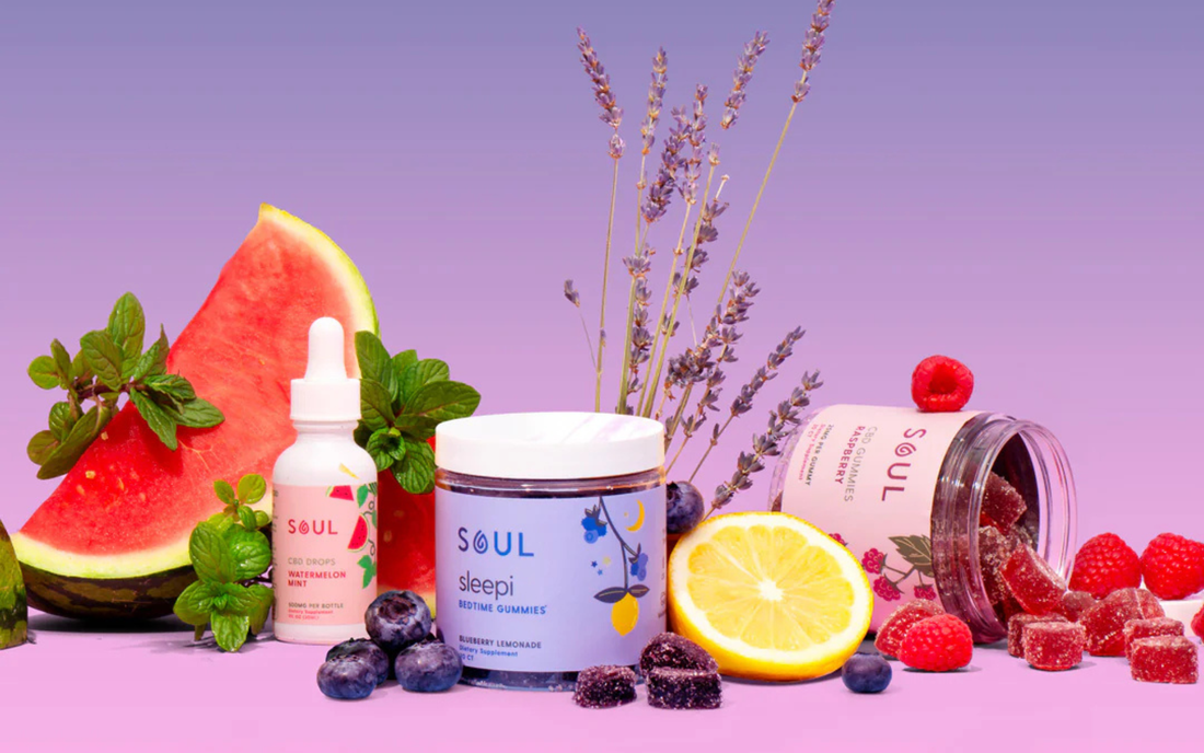 Soul CBD products arranged with watermelon, lemon, blueberries, raspberries and lavender on a purple gradient background