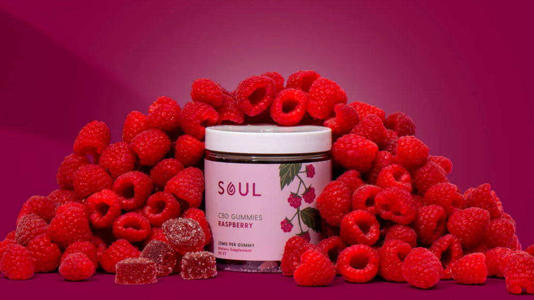 Front of Soul raspberry CBD gummies jar, pink label says 25 mg, surrounded by raspberries on magenta background