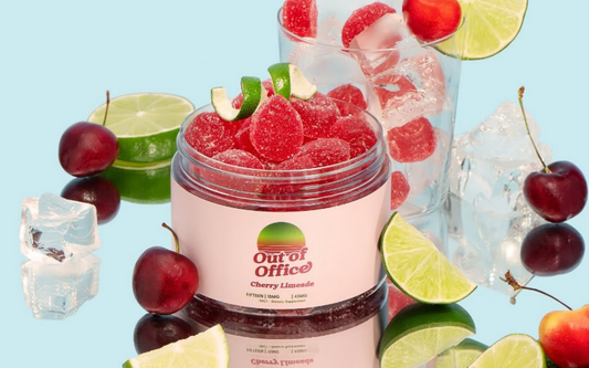 Open Out of Office Cherry Limeade jar with sugar-coated red gummies, lime wedges and cherries on pale blue background