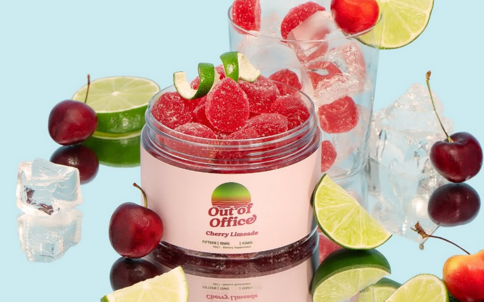 Open Out of Office Cherry Limeade jar with sugar-coated red gummies, lime wedges and cherries on pale blue background