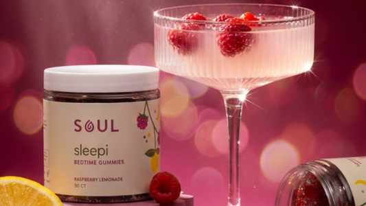 Front of SOUL Sleepi Bedtime Gummies jar showing label Raspberry Lemonade 30 ct beside a coupe glass with raspberries on pink bokeh background
