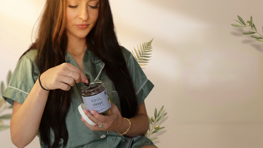 Woman in green pajamas scooping a gummy from a jar labeled Soul Sleepi while seated against a soft beige background