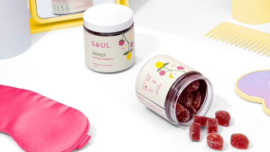 Front view of SOUL Sleepi bedtime gummies jar showing open jar with raspberry lemonade gummies spilled on white background