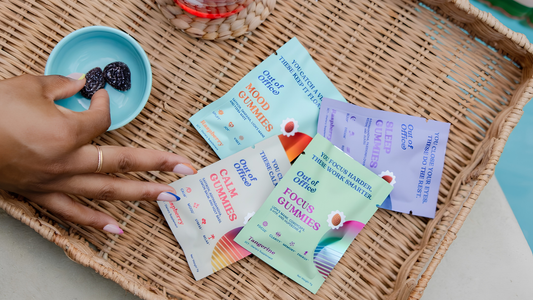 Overhead of Out of Office gummy packets in a wicker basket, with a hand picking a gummy from a small blue dish